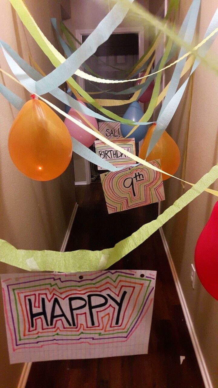 some balloons and streamers are hanging from the ceiling in front of a happy birthday sign