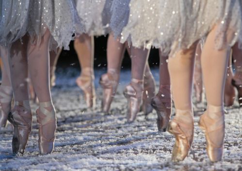 several ballerinas are walking down the street in their ballet outfits and shoes with snow falling all over them