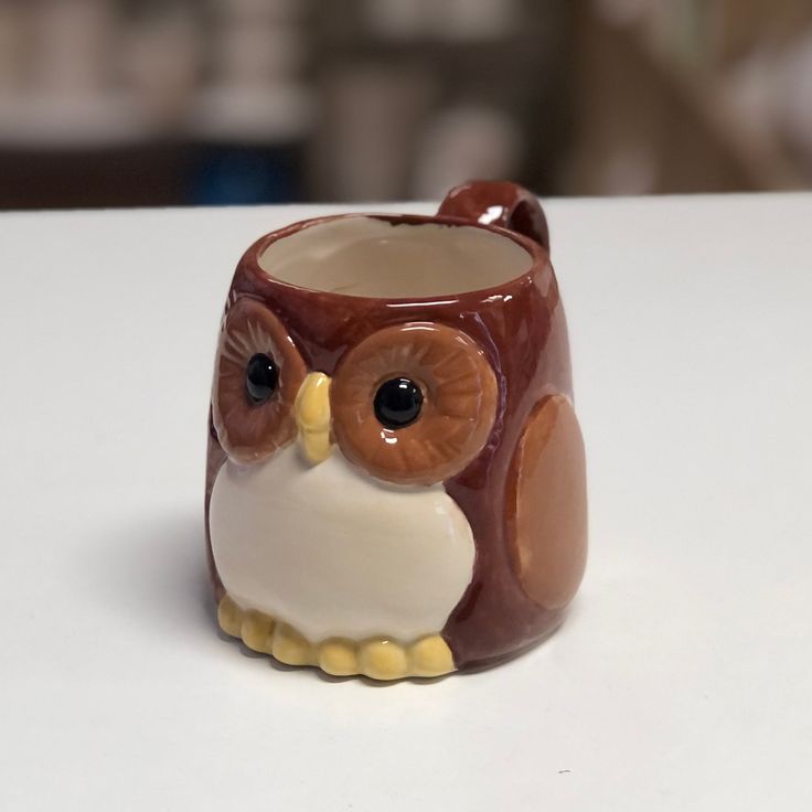 a brown and white owl mug sitting on top of a table