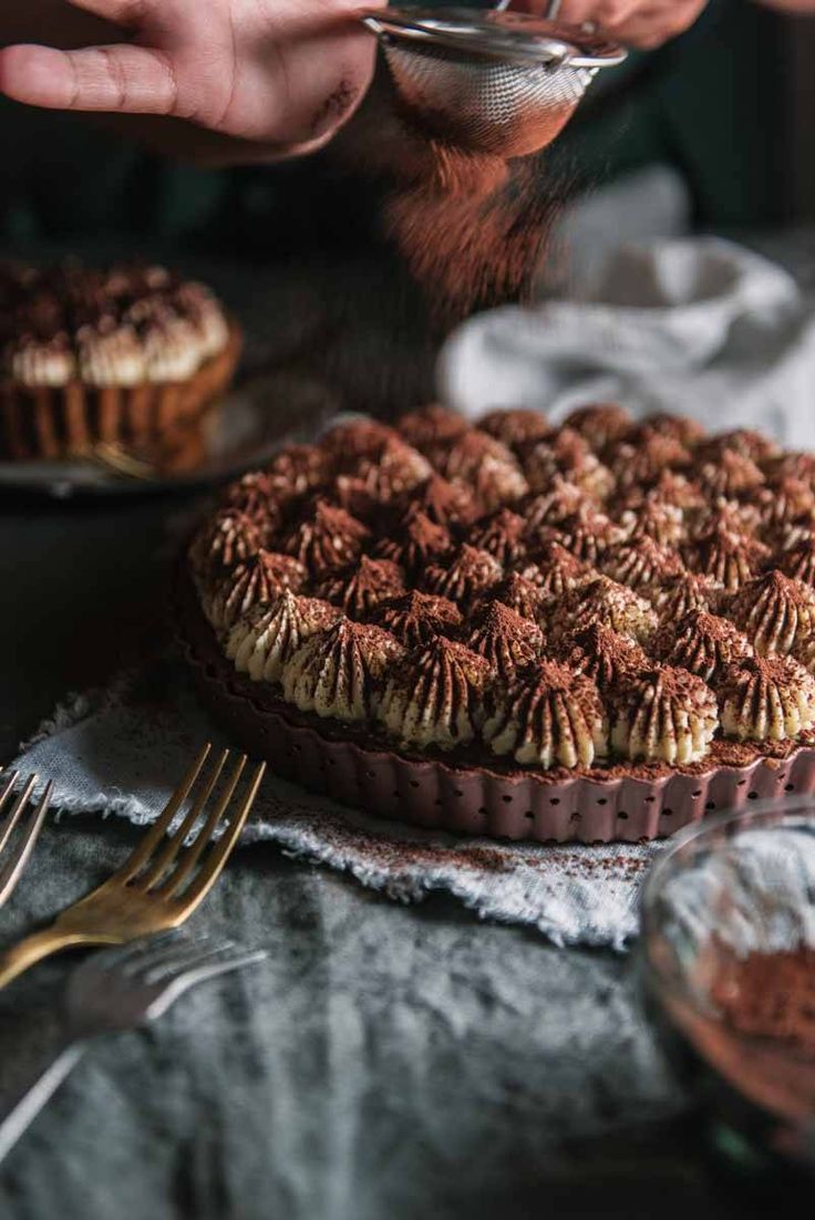 someone is decorating a chocolate tart with icing