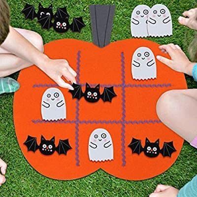 children are playing with halloween decorations on the grass in front of a pumpkin shaped rug