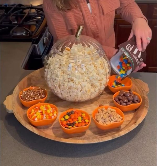 a woman pouring candy into small bowls on a tray