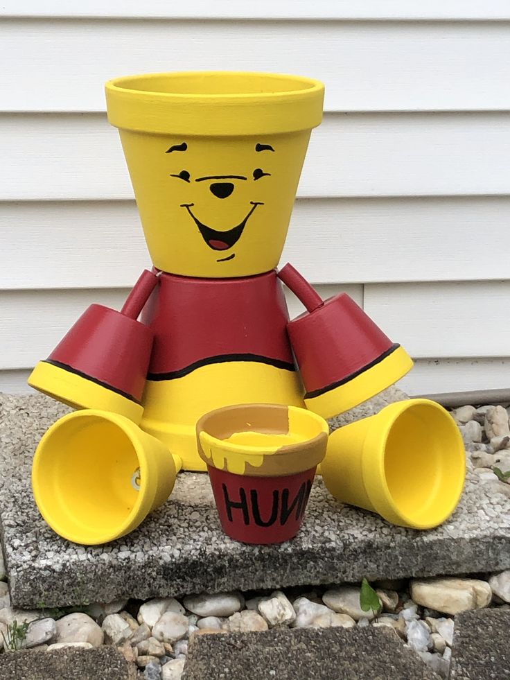 a yellow and red toy sitting on top of a cement block next to a cup