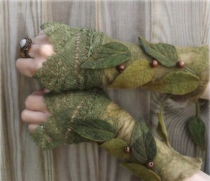 two hands are covered with green leaves and beads