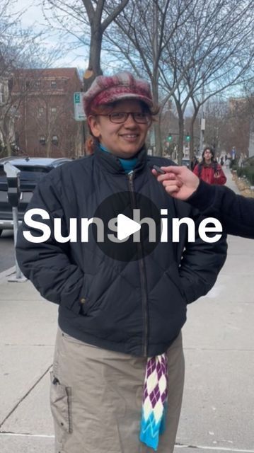 a woman is standing on the sidewalk with her hands in her pockets and smiling at the camera