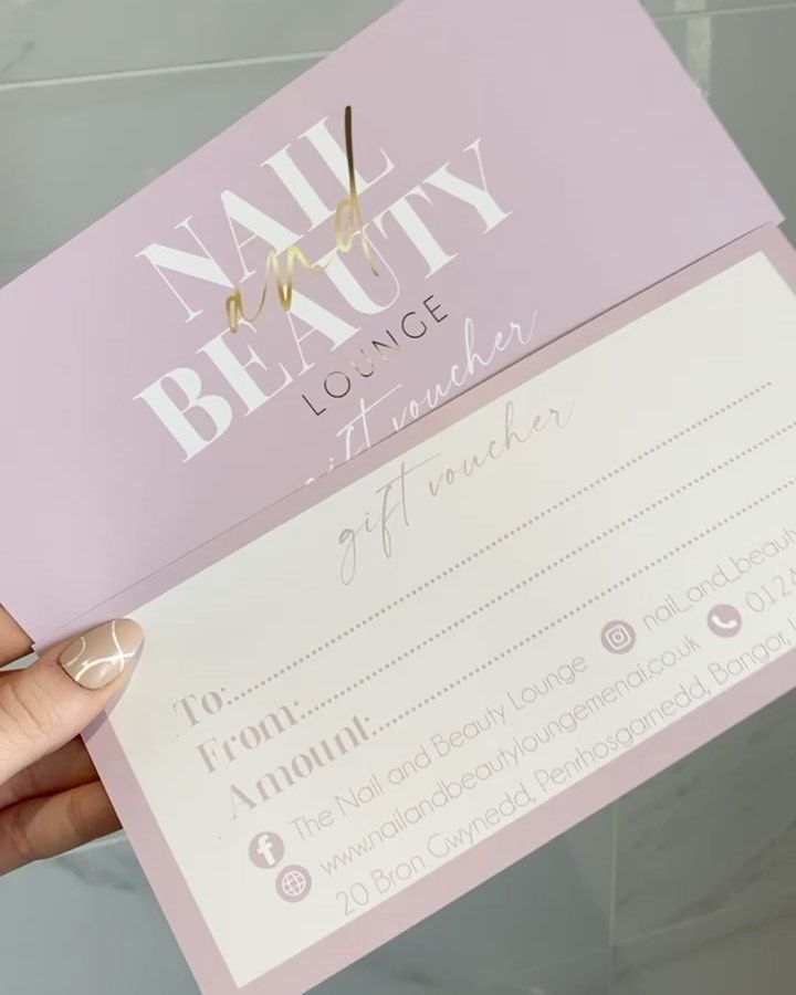 a person holding up a pink and white business card with gold foil lettering on it