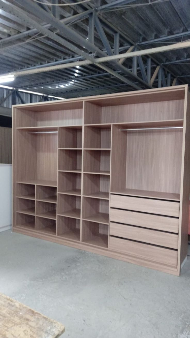 an empty storage room with wooden shelves and drawers