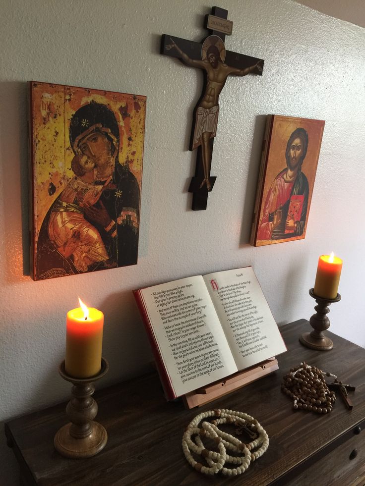 an open book sitting on top of a wooden table next to a cross and two candles