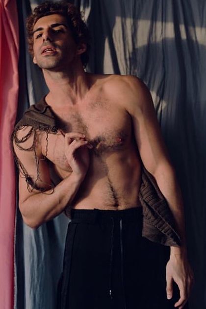 a shirtless man standing in front of a curtain with his hands on his chest