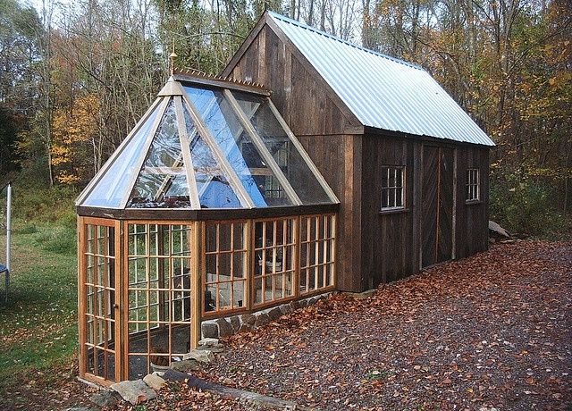 a small wooden building with a glass window on the side and a metal roof over it