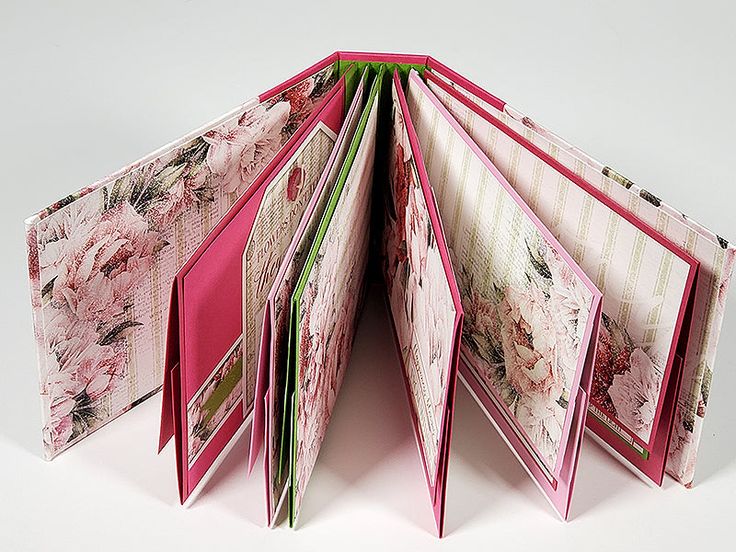 an open book with pink and green pages on the inside, sitting in front of a white background