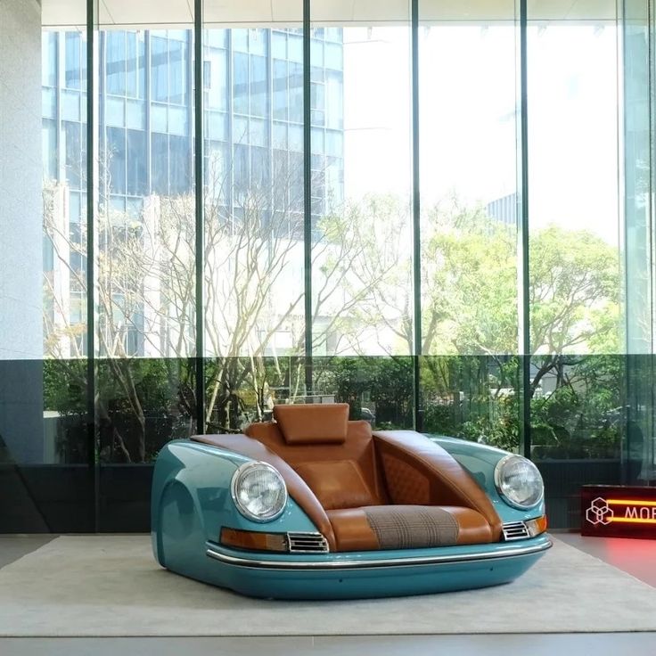 a car shaped like a couch sitting in front of a window next to a sign