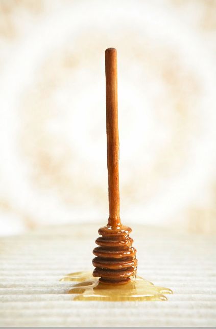 a honey drizzled on top of a stack of pancakes with a wooden stick sticking out of it