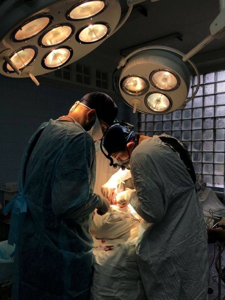 three doctors performing surgery on a baby in an inclosure