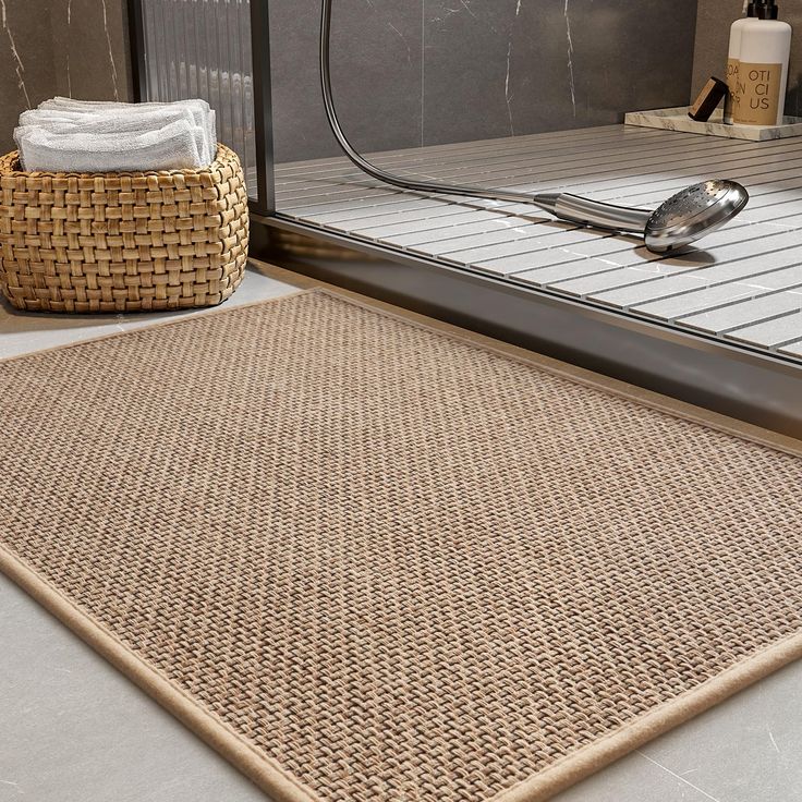 a close up of a bathroom rug on the ground near a shower door with a spoon and towel