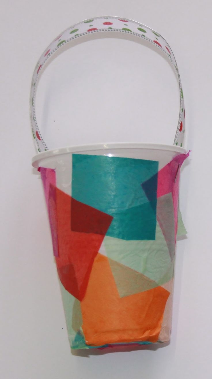 a paper basket hanging on the wall with some tape around it's handles and bottom