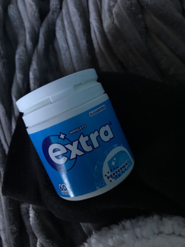 a bottle of extra sitting on top of a pile of blankets next to a blanket