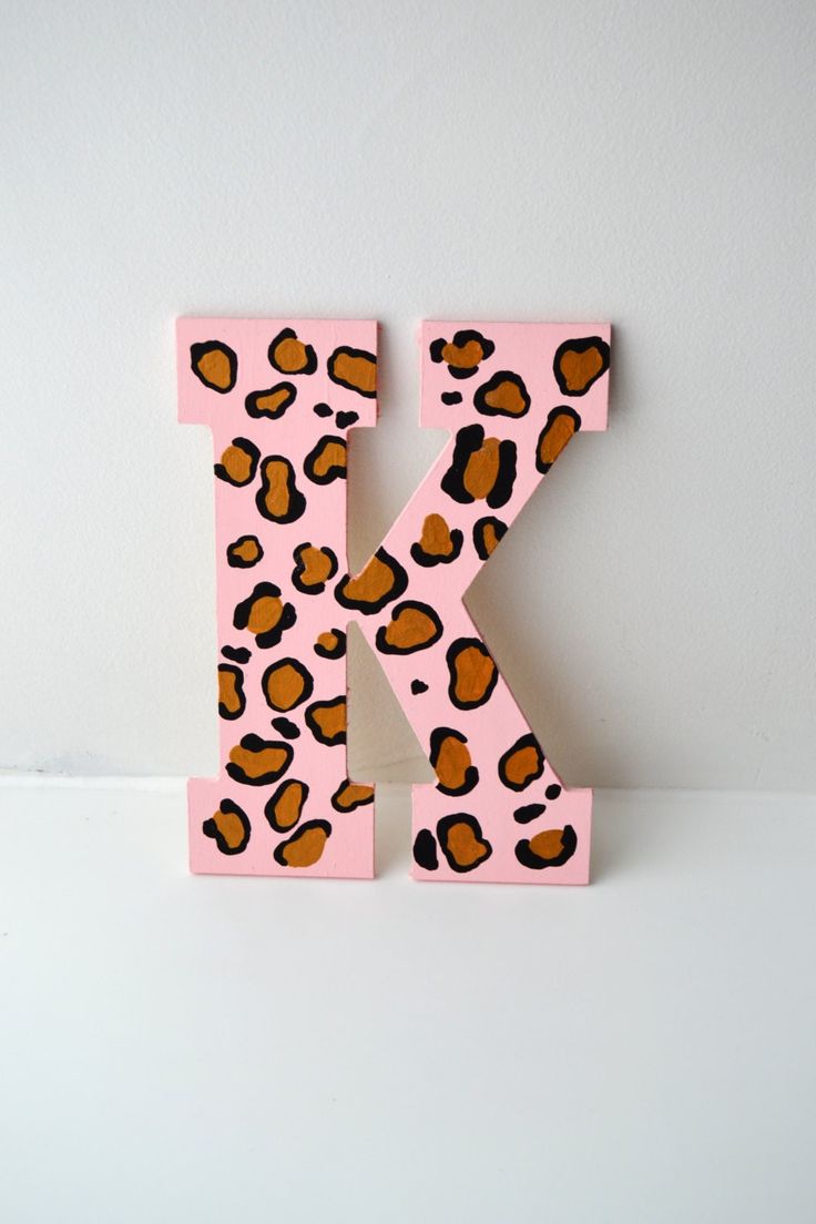 the letter k is made up of pink and brown leopard print letters with black spots