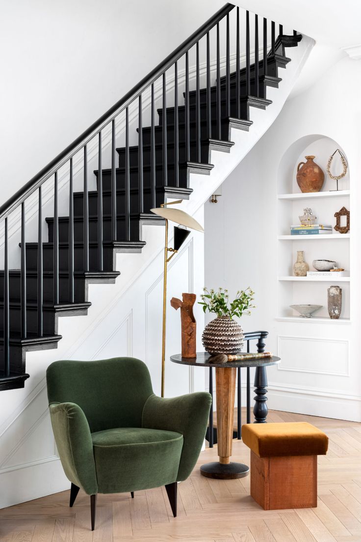 a living room with two chairs and a table in front of a stair case on the wall