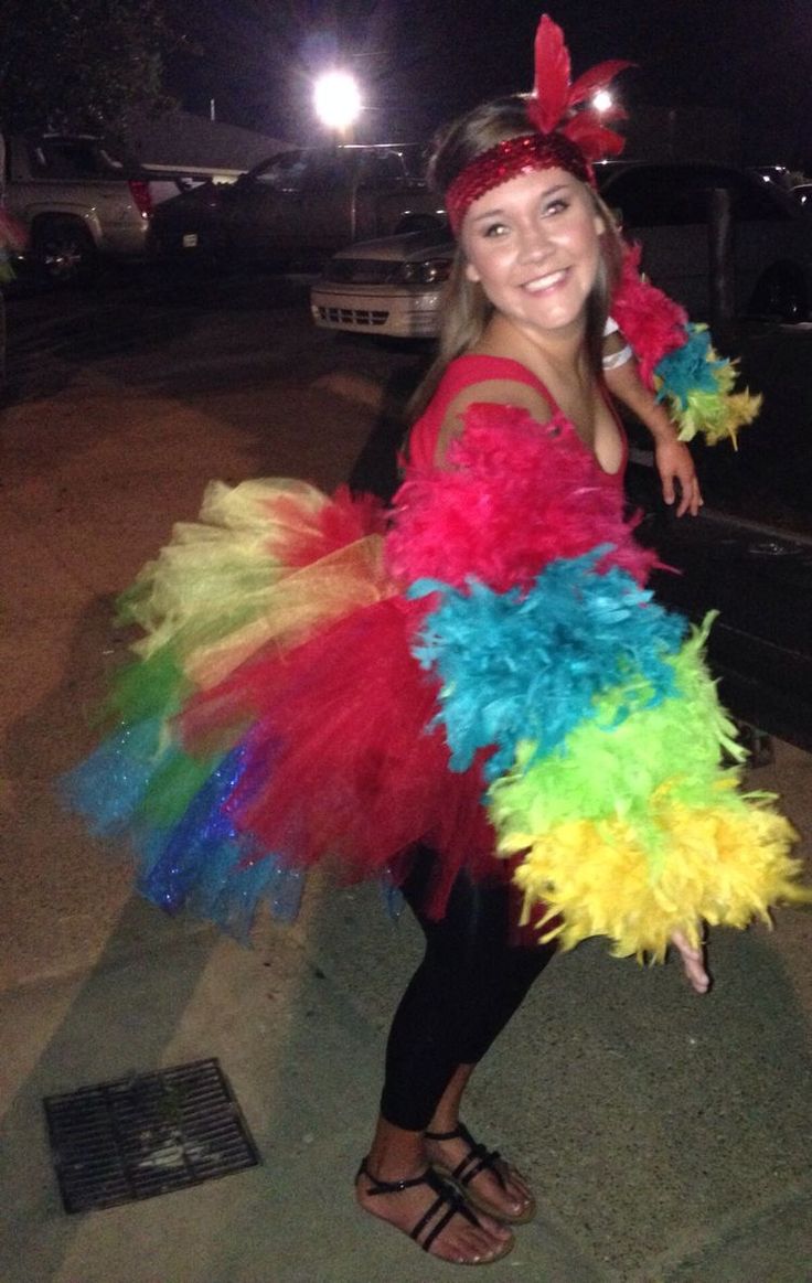 a woman in a colorful costume standing on the sidewalk with her arms around her waist