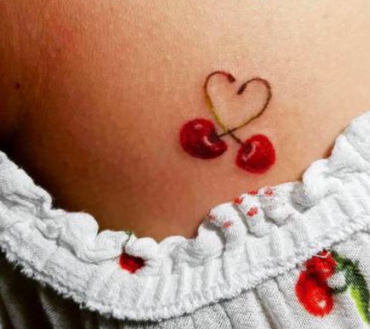 a small cherry tattoo on the back of a woman's stomach, with two cherries in the shape of a heart