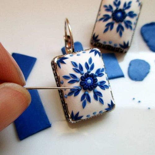 a person is holding onto some kind of blue and white flowered square shaped brooch