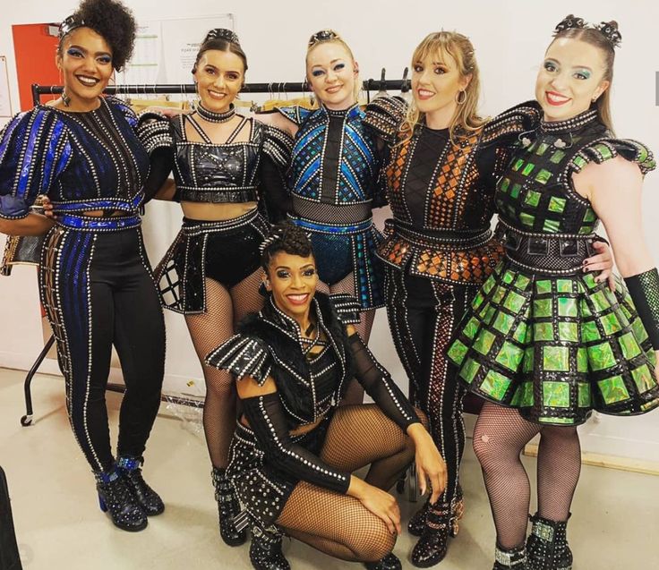 a group of women standing next to each other wearing costumes and posing for the camera