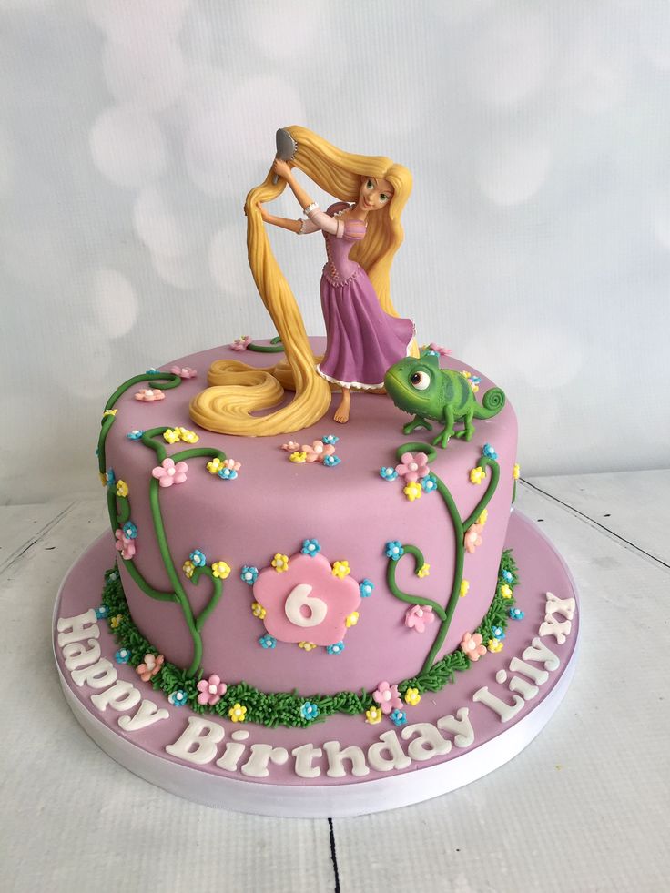 a birthday cake with a princess and frog on top, decorated in pink frosting