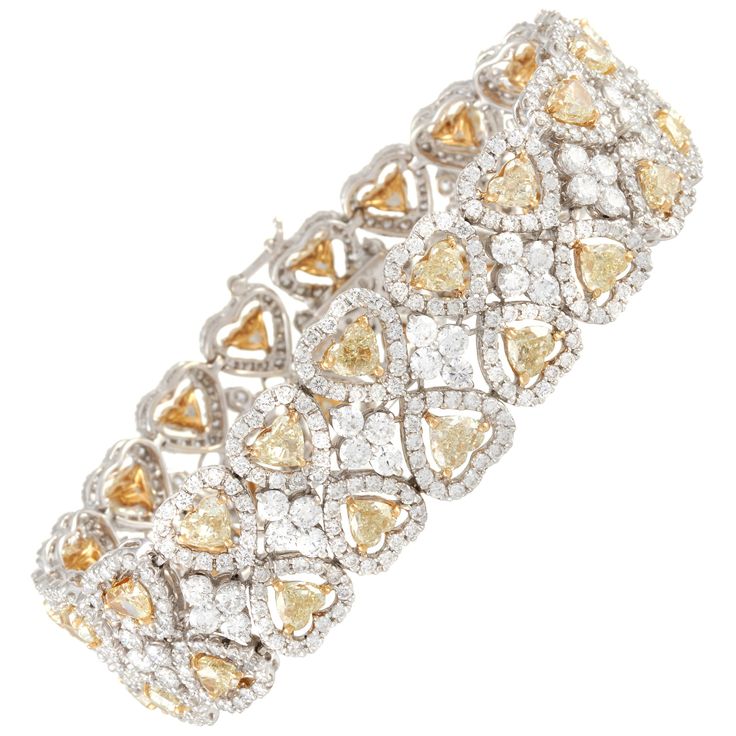 A 18-karat white and yellow gold diamond bracelet with two rows of heart shape diamonds with white diamond halos. There are 38 Fancy Yellow heart diamonds that weight about 13.50 carats with a VS clarity. There are 612 round white diamonds that weigh about 12.54 carats with a G-H color and VS clarity. Total diamond weight for the bracelet: ~26.04 carats. Gold Diamond Bracelet, Heart Shaped Jewelry, Yellow Heart, Bracelets Gold Diamond, Heart Shaped Diamond, Expensive Jewelry, Yellow Diamond, Diamond Bracelets, Diamond Heart