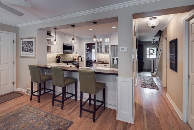 a kitchen with an island and bar stools in the center, along with two dining room chairs