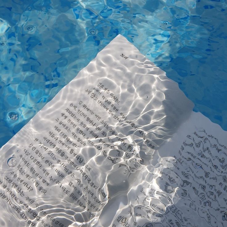 an open book sitting on top of a sheet of paper next to a swimming pool