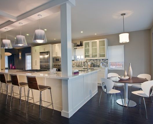 a large open concept kitchen and dining room with white cabinets, stainless steel appliances and bar stools