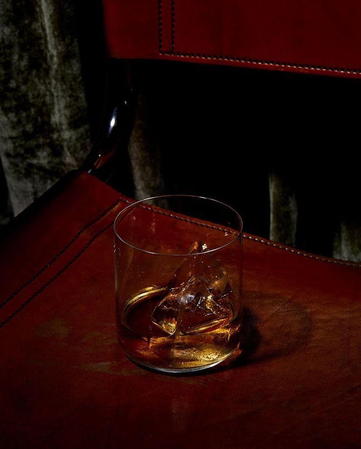 a glass filled with liquid sitting on top of a wooden table next to a red chair