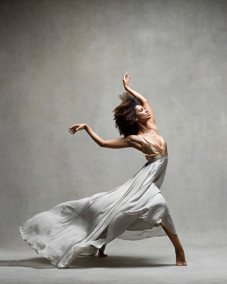 a woman in a white dress is dancing with her arms spread out to the side