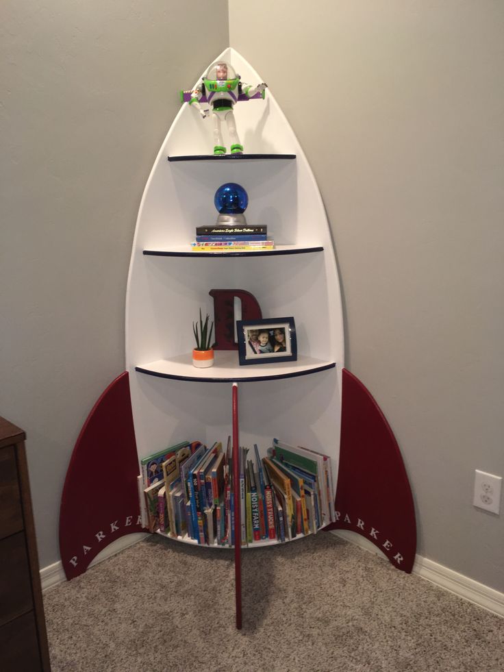 there is a book shelf in the corner with books on it and an airplane shaped shelf