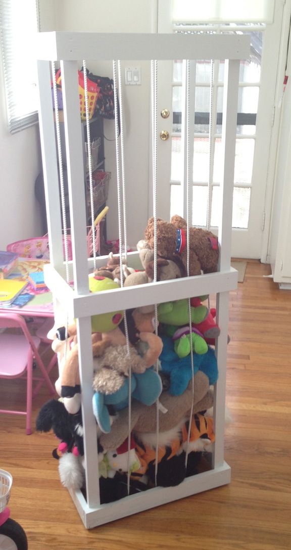 a white cage filled with stuffed animals on top of a hard wood floor next to a door