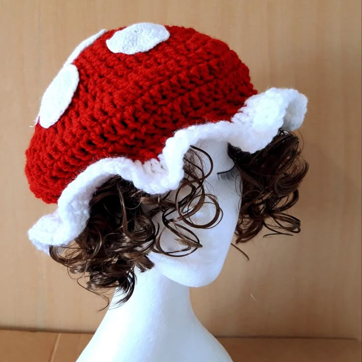 a white mannequin head wearing a red and white knitted mushroom hat