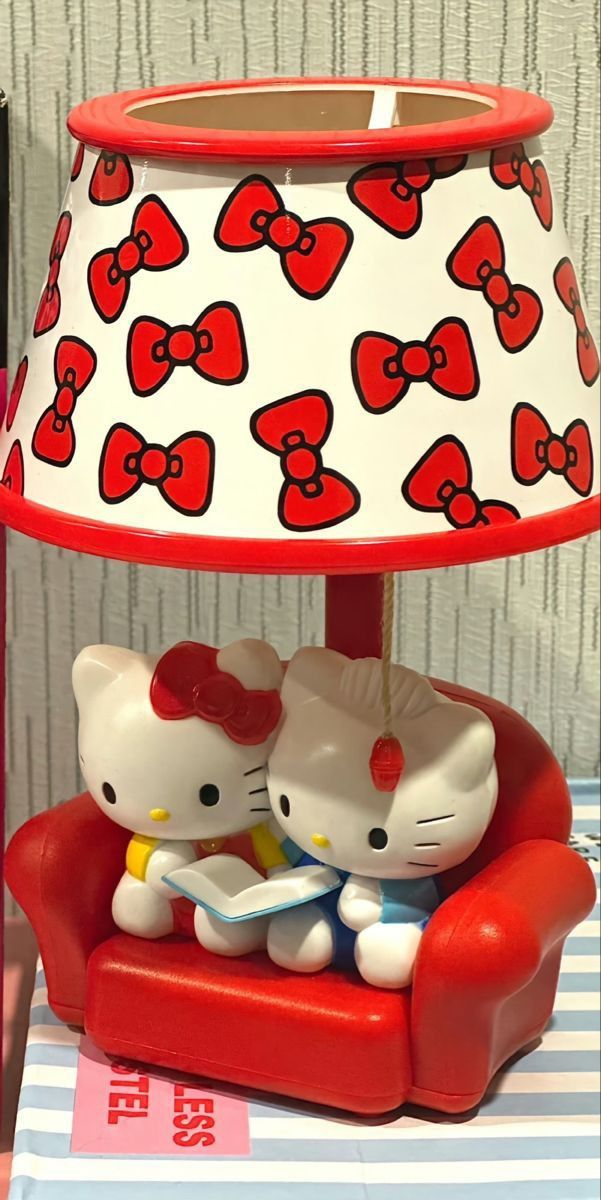 a hello kitty lamp sitting on top of a red chair next to a white and red lampshade