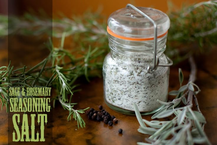 a jar filled with salt sitting on top of a wooden table next to some herbs