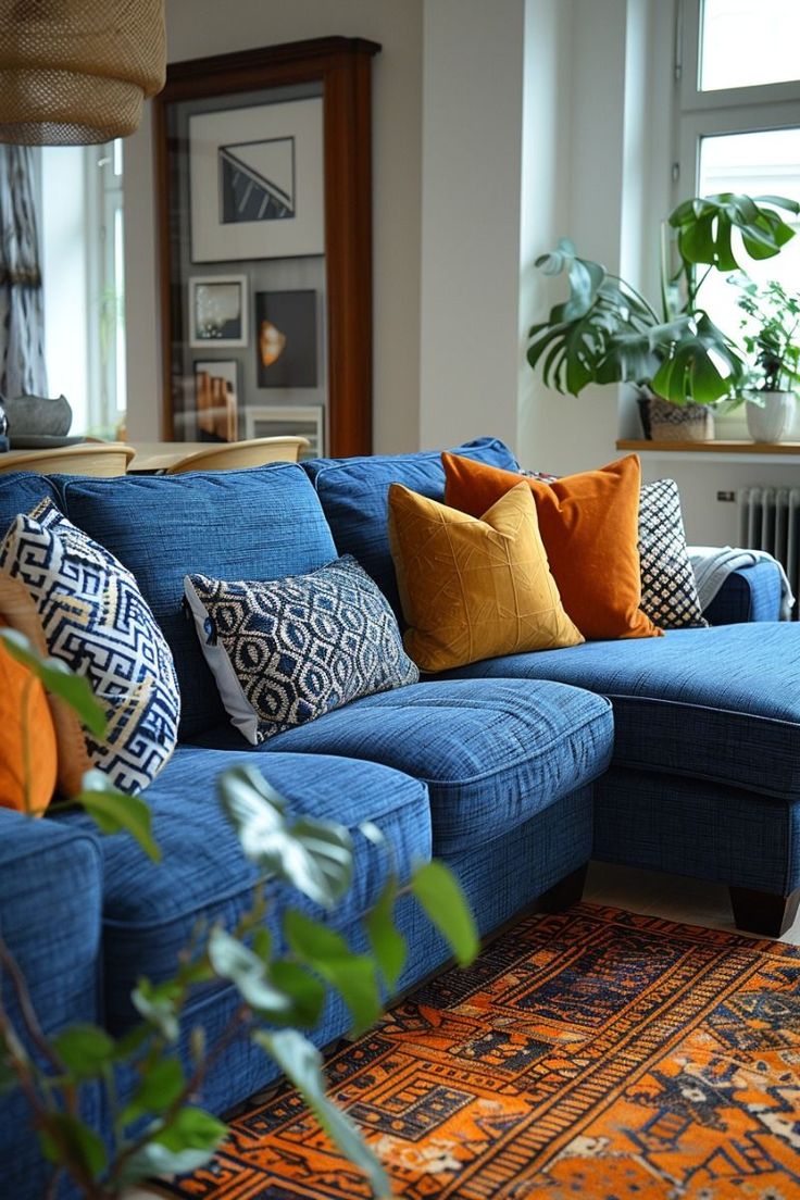 a living room with blue couches and colorful pillows on the floor next to a window