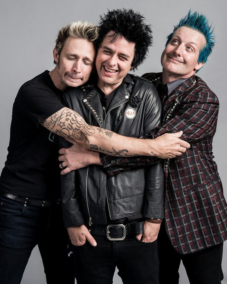 two men hugging each other while wearing black leather jackets and tattoos on their arms, both with blue hair