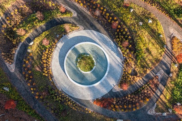 an aerial view of a circular garden in the middle of a park with lots of trees