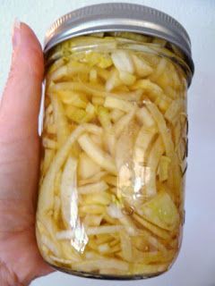 a person is holding a jar full of pickled up pasta in it's left hand