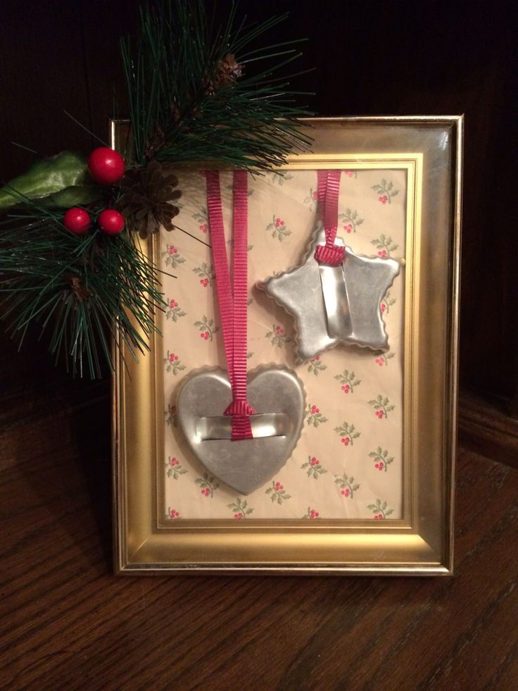 two ornaments are hanging in a frame on the floor next to a christmas tree branch