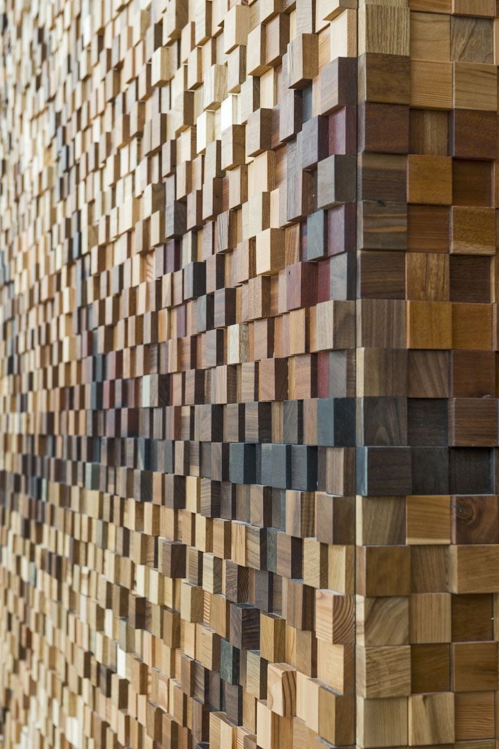 a wall made out of wooden planks with different colors and shapes on the side