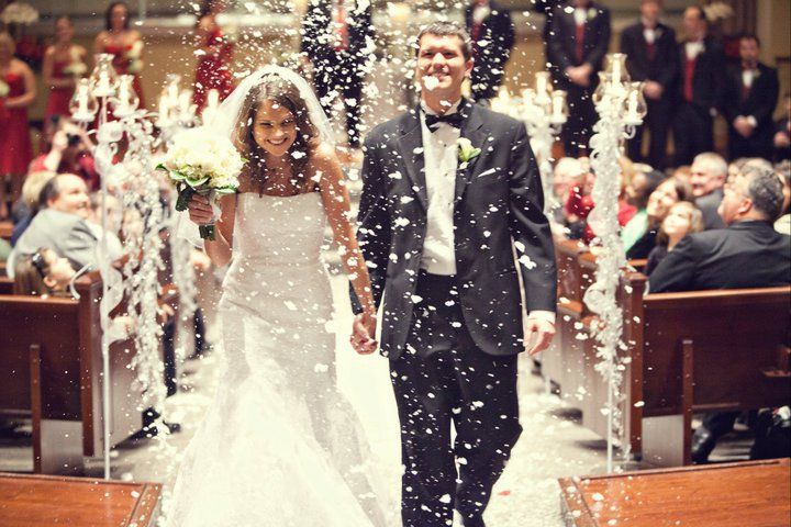 a bride and groom walk down the aisle as confetti is thrown around them