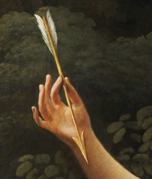 a hand holding a feather on top of a river