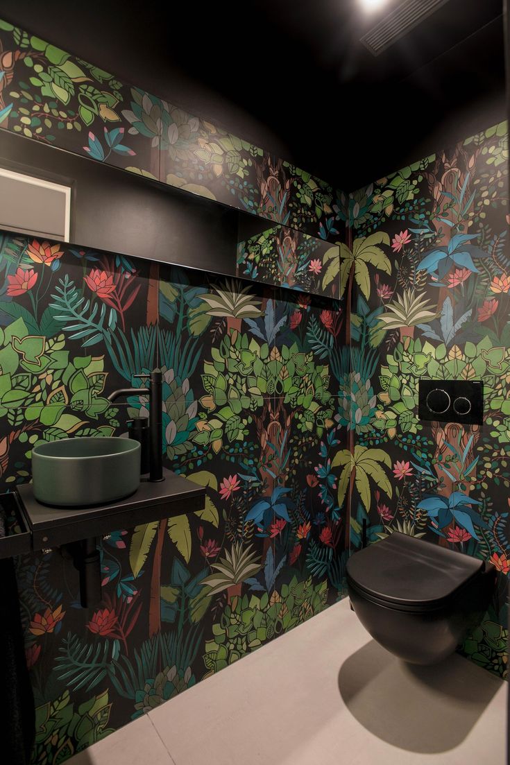 a bathroom with colorful wallpaper and black toilet in the corner, next to a sink