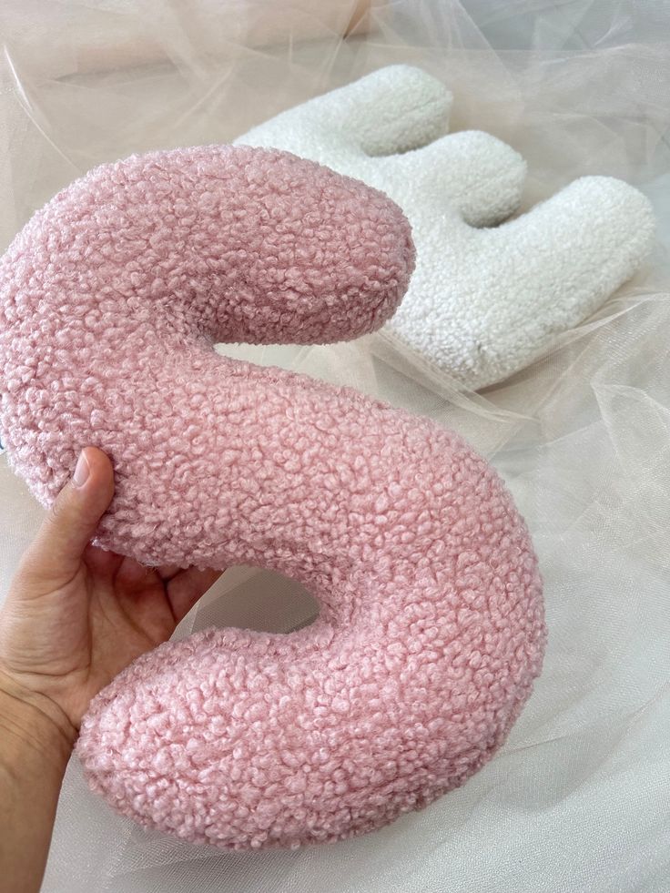 a person holding a pink and white donut shaped pillow