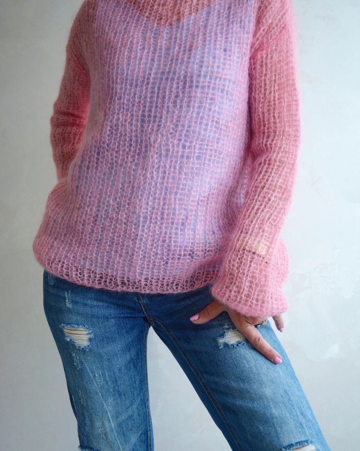 a woman wearing ripped jeans and a pink sweater